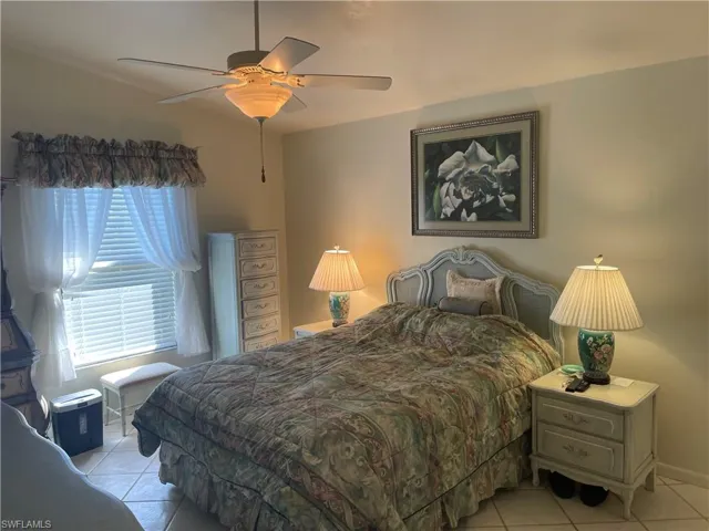 Bedroom with ceiling fan, light tile patterned flooring, and baseboards
