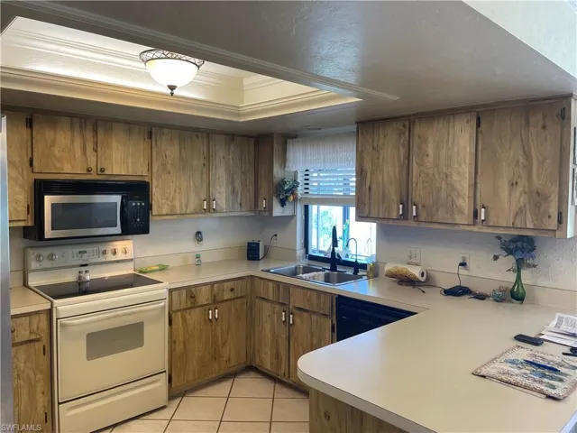Kitchen with light tile patterned floors, white electric range, a sink, black dishwasher, and light countertops