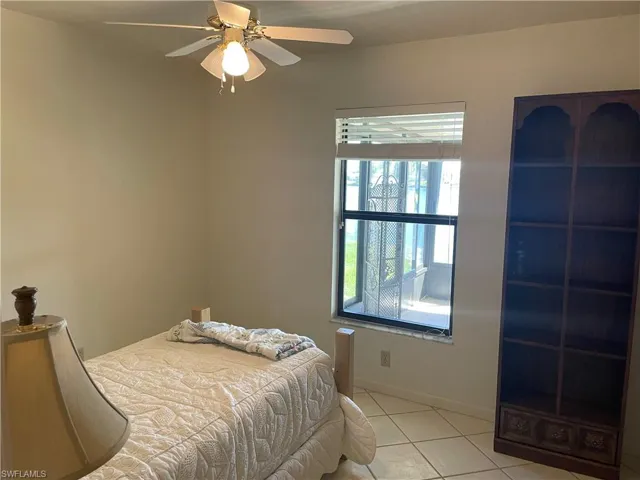 Bedroom featuring light tile patterned floors, ceiling fan, and baseboards