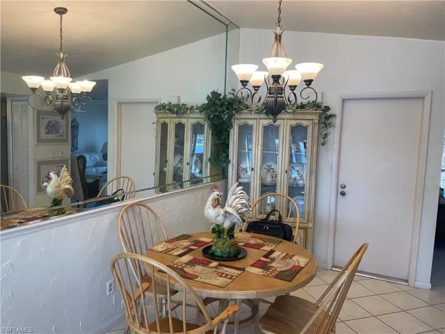 Dining space with lofted ceiling, a notable chandelier, and light tile patterned flooring