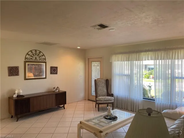 Living area with light tile patterned floors, a textured ceiling, and visible vents