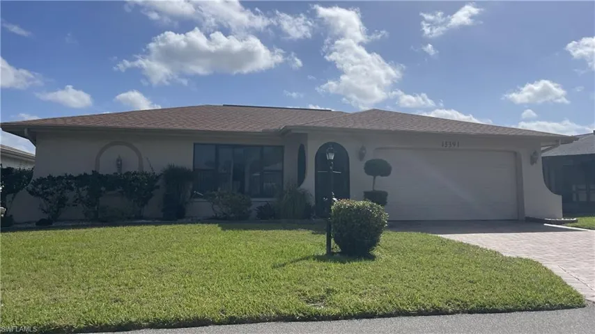 Ranch-style home with a front yard, an attached garage, and stucco siding