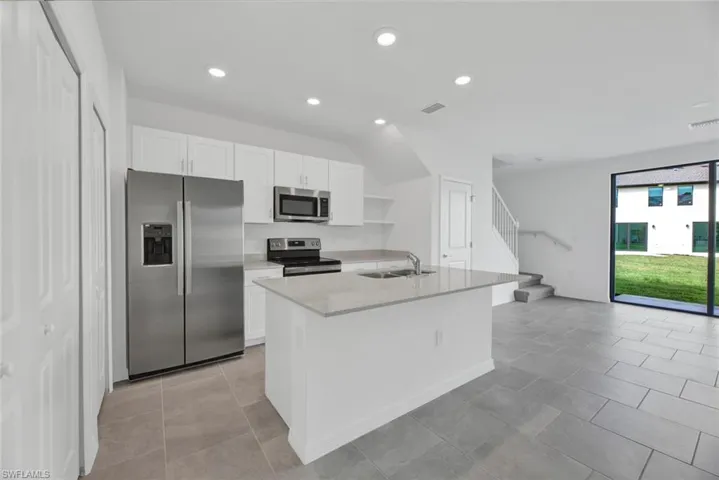 Kitchen featuring appliances with stainless steel finishes, open shelves, white cabinetry, recessed lighting, and light stone countertops