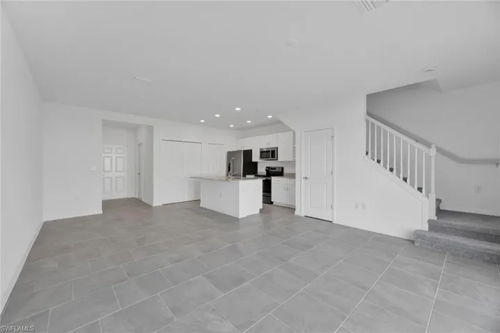 Unfurnished living room with stairway, recessed lighting, and light tile patterned floors