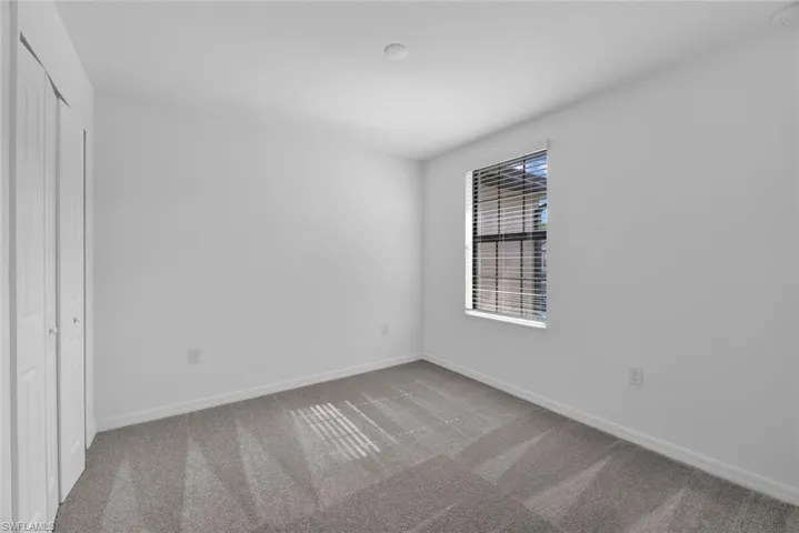 Unfurnished bedroom with light carpet and a closet
