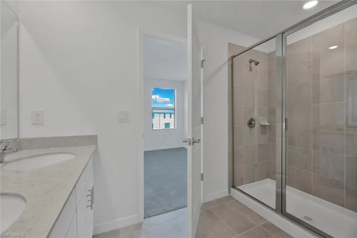 Full bathroom with light tile patterned flooring, double vanity, and a stall shower