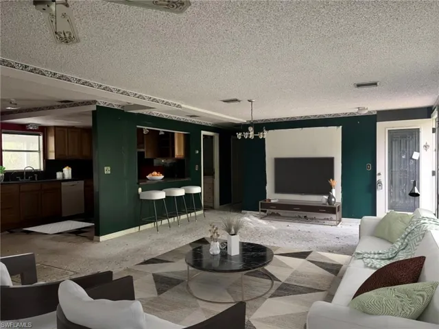 Carpeted living room with sink, a textured ceiling, and a chandelier
