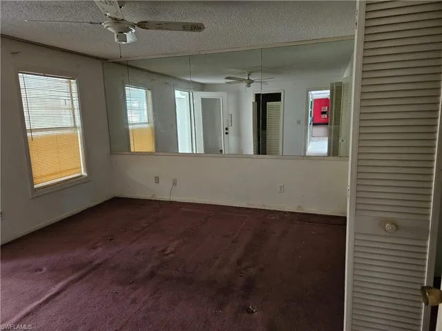 Carpeted spare room featuring a textured ceiling and ceiling fan
