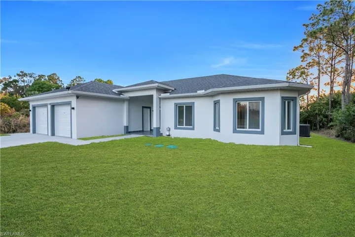 View of front facade with a front yard, stucco siding, a garage, driveway, and roof with shingles