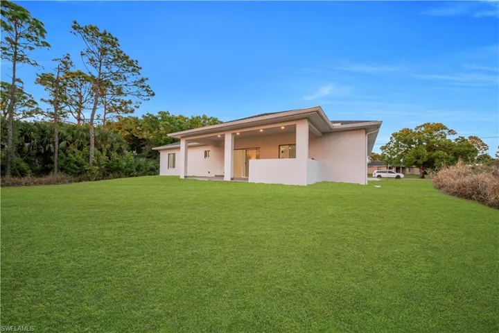 Rear view of property featuring a lawn, stucco siding, and a patio area