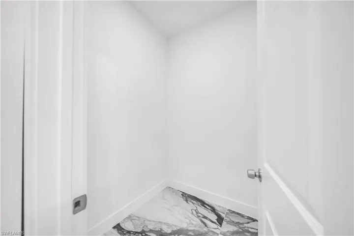 Laundry room featuring baseboards and light marble finish flooring
