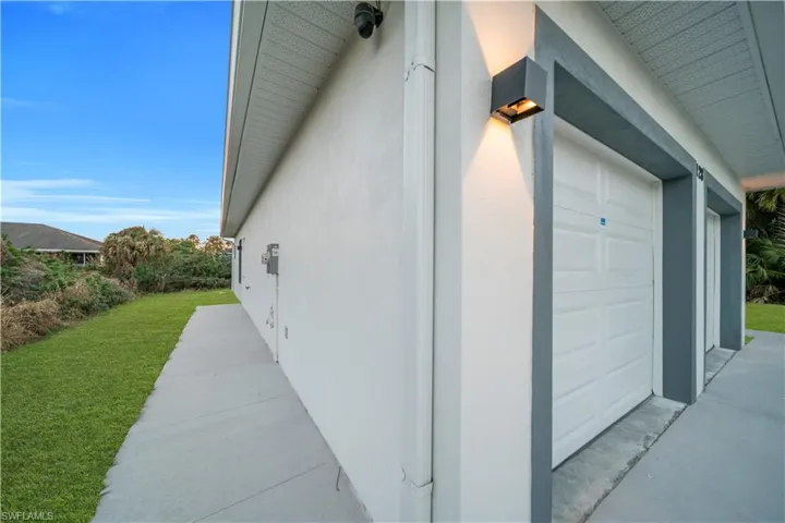 View of side of property featuring a garage, a yard, and stucco siding