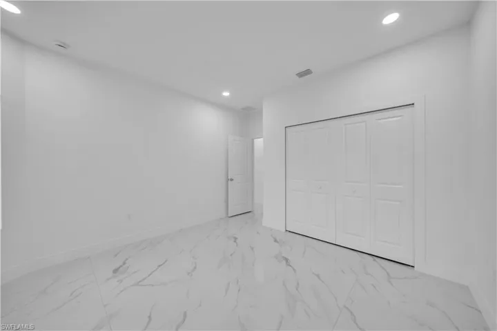 Unfurnished bedroom with light marble finish floors, recessed lighting, and a closet