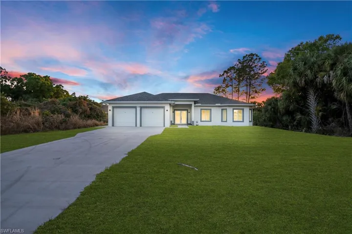 View of front of house featuring a front yard, an attached garage, driveway, and stucco siding