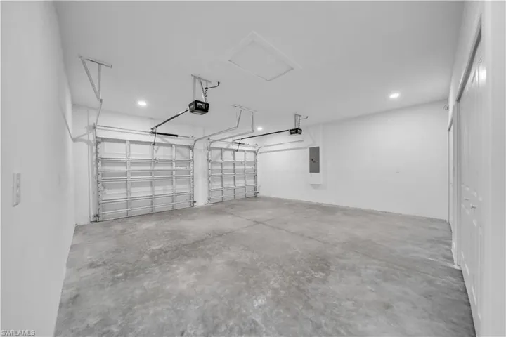 Garage with recessed lighting, electric panel, and a garage door opener