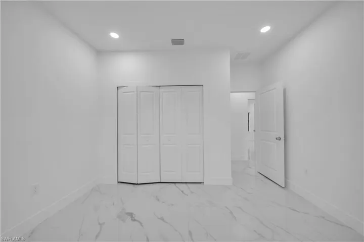 Unfurnished bedroom featuring recessed lighting, light marble finish floors, and a closet