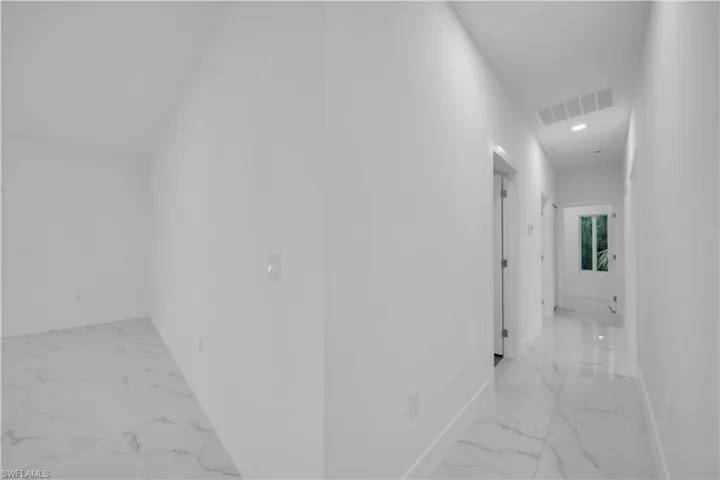 Corridor with light marble finish floors and recessed lighting