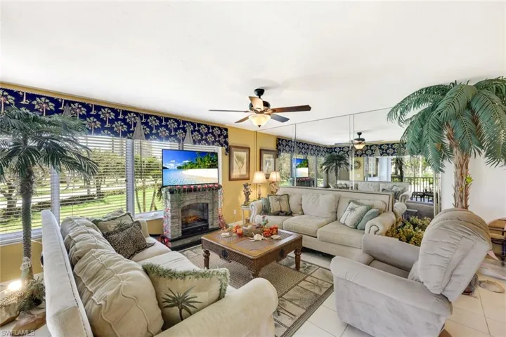 Living area featuring light tile patterned floors, a fireplace with raised hearth, and ceiling fan