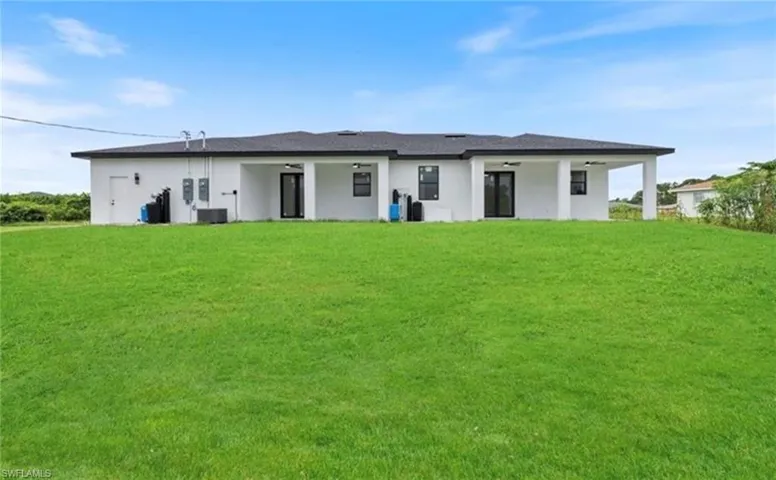 Rear view of property featuring a lawn and stucco siding