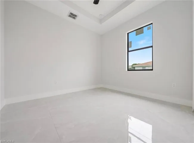 Empty room featuring a tray ceiling and concrete flooring