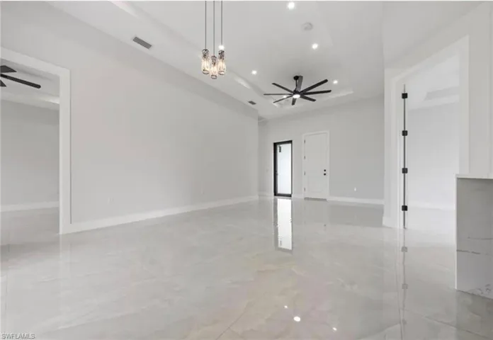 Unfurnished room with ceiling fan, a raised ceiling, and a chandelier