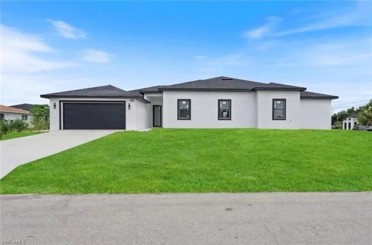 Prairie-style home featuring a front yard, driveway, stucco siding, and a garage