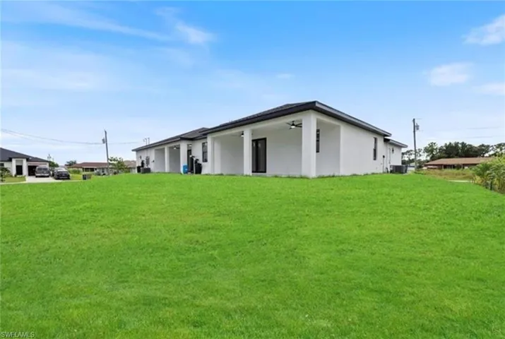 Back of property with a lawn, ceiling fan, and a patio area
