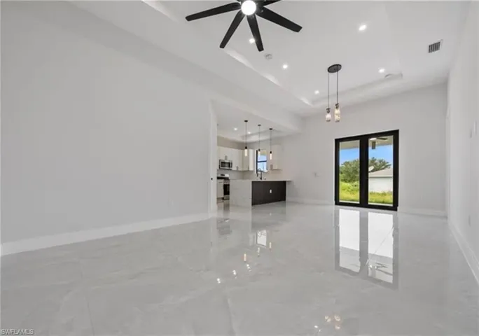 Unfurnished living room with light marble finish floors, recessed lighting, a ceiling fan, and a tray ceiling