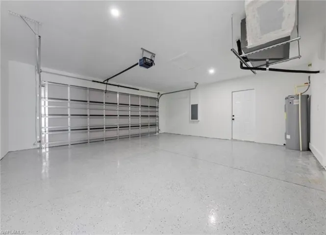 Garage featuring electric water heater, a garage door opener, and electric panel