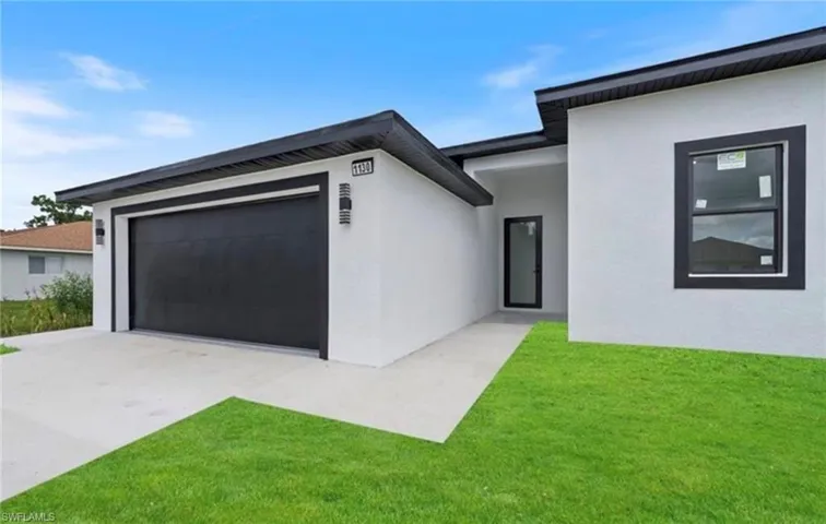 View of front of house with stucco siding, driveway, a front lawn, and an attached garage