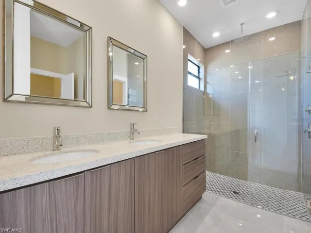 Full bath with double vanity, a stall shower, and recessed lighting