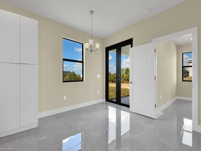 Unfurnished dining area with a chandelier, french doors, and light marble finish flooring