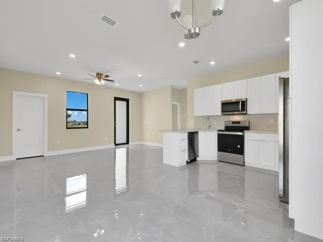 Kitchen featuring stainless steel appliances, a peninsula, open floor plan, white cabinets, and recessed lighting