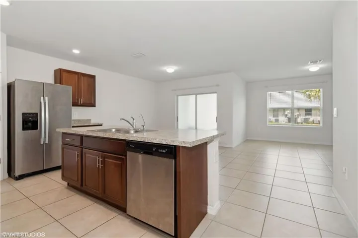 Kitchen with an island with sink, stainless steel appliances, light tile flooring, and sink