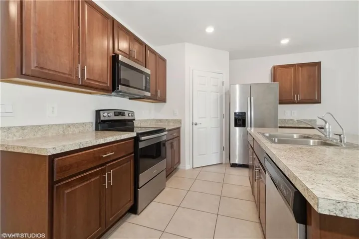Kitchen with stainless steel appliances, sink, and light tile floors
