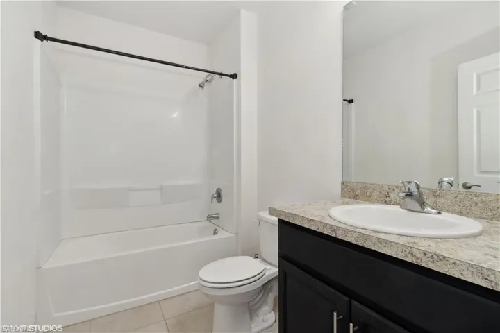 Full bathroom featuring tile floors, vanity, toilet, and shower / bathing tub combination