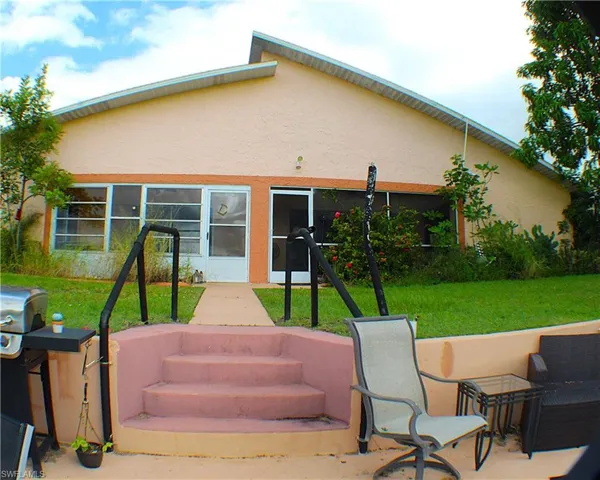 Rear view of property featuring stucco siding and a yard