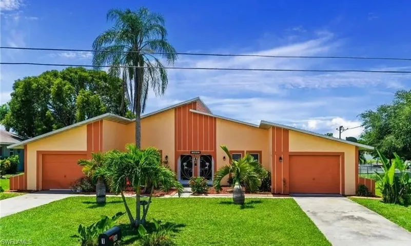Mid-century inspired home with a garage, a front lawn, concrete driveway, and stucco siding
