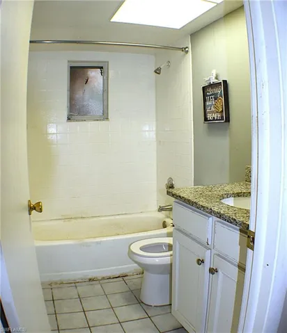 Full bath with vanity, shower / bath combination, light tile patterned flooring, and a skylight
