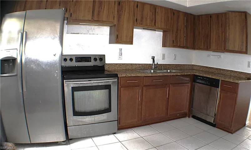 Kitchen featuring dark countertops, appliances with stainless steel finishes, and light tile patterned floors