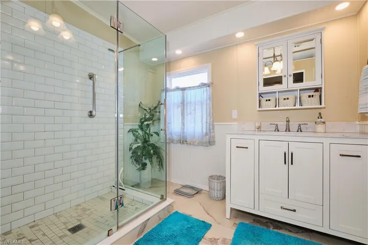 Full bath with a shower stall, wainscoting, recessed lighting, marble finish floor, and vanity