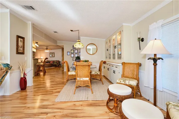 Dining area with ornamental molding, visible vents, light wood-type flooring, and wainscoting