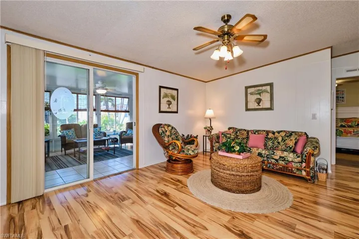 Living area with wood finished floors, a textured ceiling, ceiling fan, and crown molding