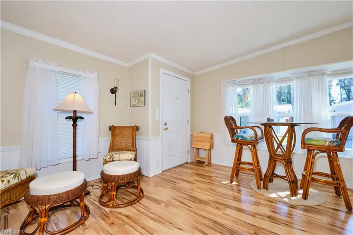 Sitting room with wainscoting, a textured ceiling, light wood-style flooring, and ornamental molding