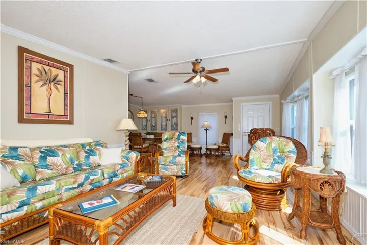 Living room featuring visible vents, wood finished floors, ornamental molding, and a ceiling fan