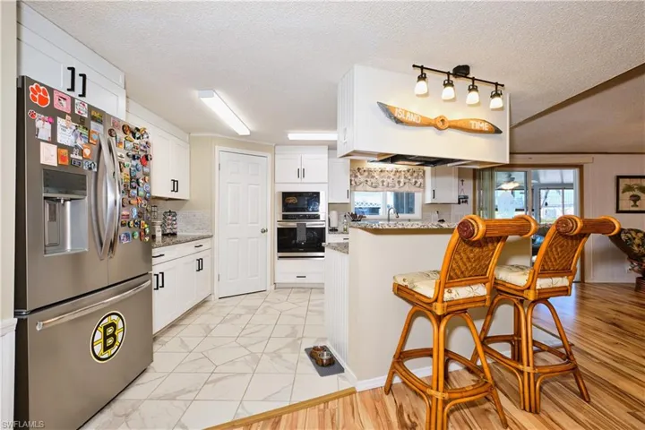 Kitchen featuring a peninsula, marble finish floor, white cabinets, and stainless steel fridge with ice dispenser
