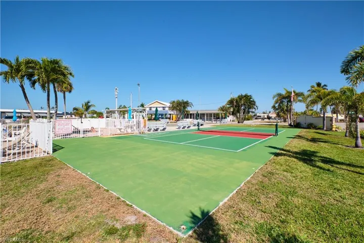 View of sport court with fence and a lawn
