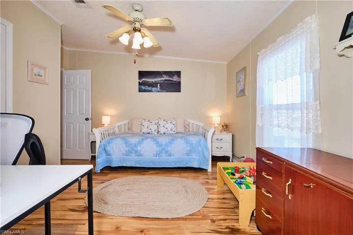 Bedroom featuring ceiling fan, crown molding, light wood finished floors, and a textured ceiling