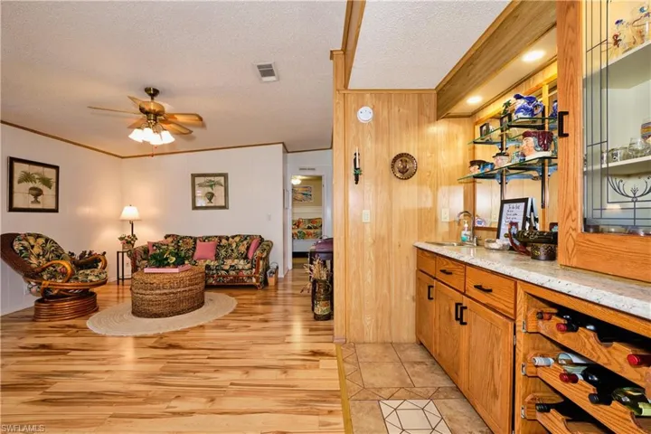 Bar featuring visible vents, ceiling fan, light wood-type flooring, ornamental molding, and a textured ceiling