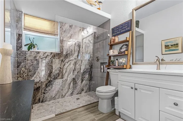 Full bathroom with a stall shower, vanity, and light wood-type flooring